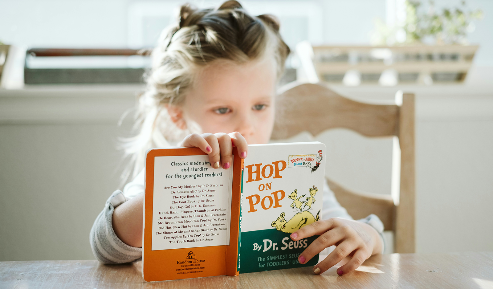 A young girl reading a Dr. Seuss book