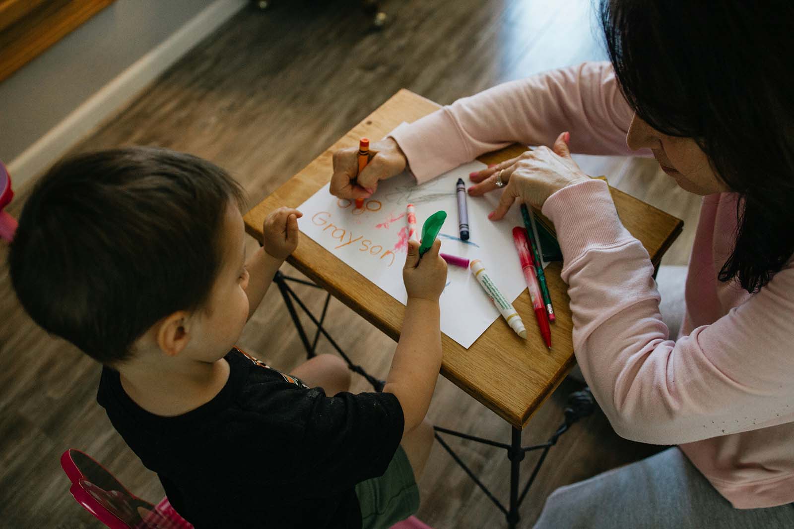 confidence young boy coloring with his teacher