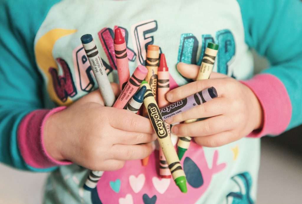 a small child holding crayons to his or her chest