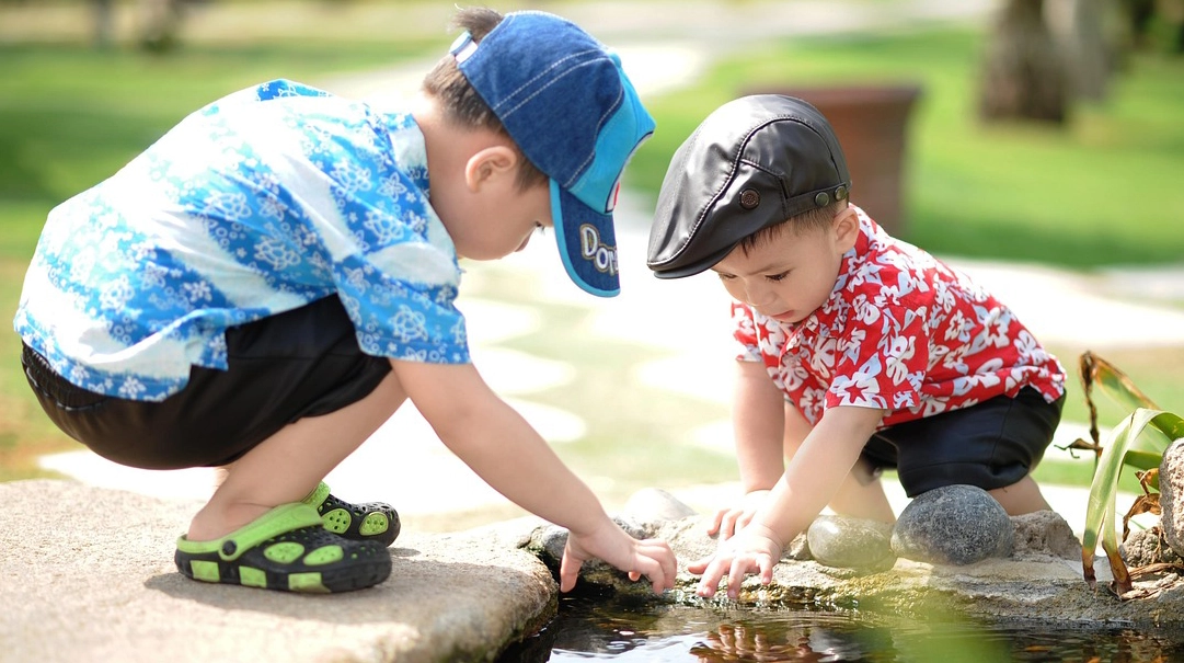 outdoorplay Two small boys playing in a pond