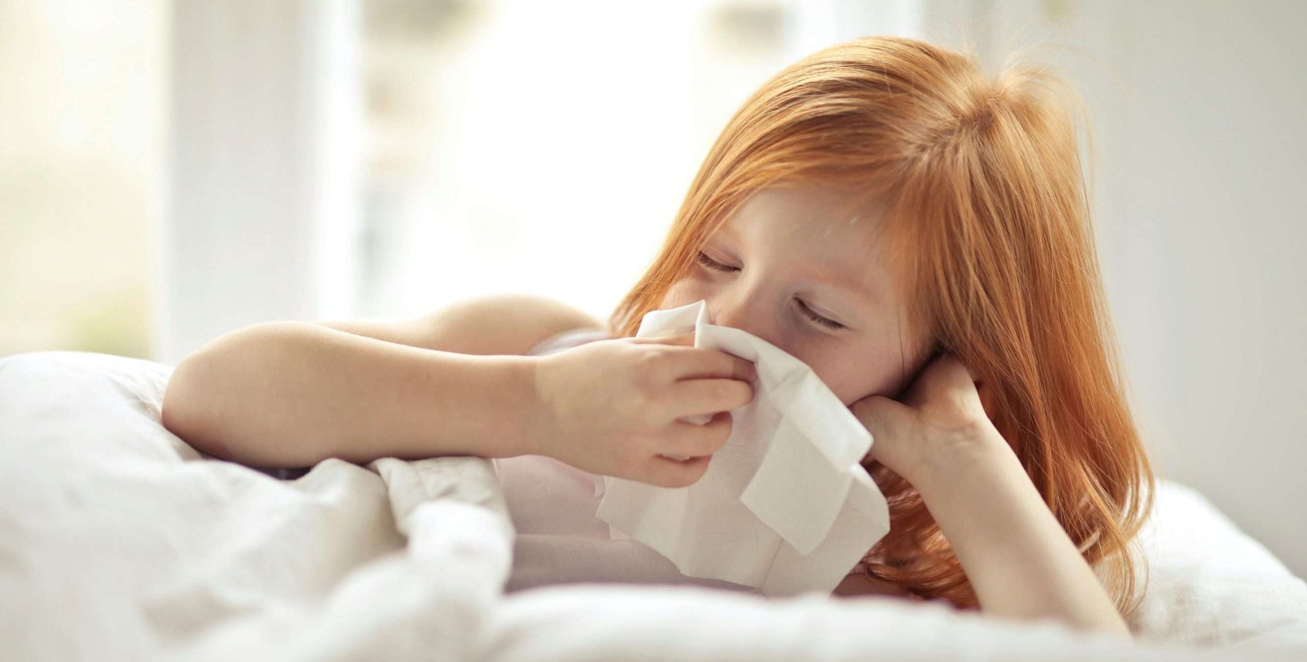 a young girl with red hair wiping her nose with a tissue
