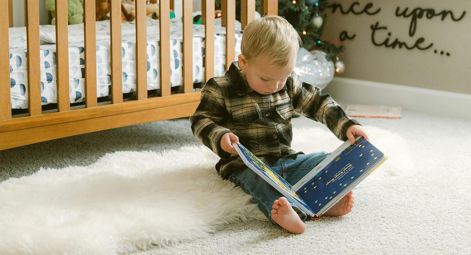 baby sitting in the floor reading a book