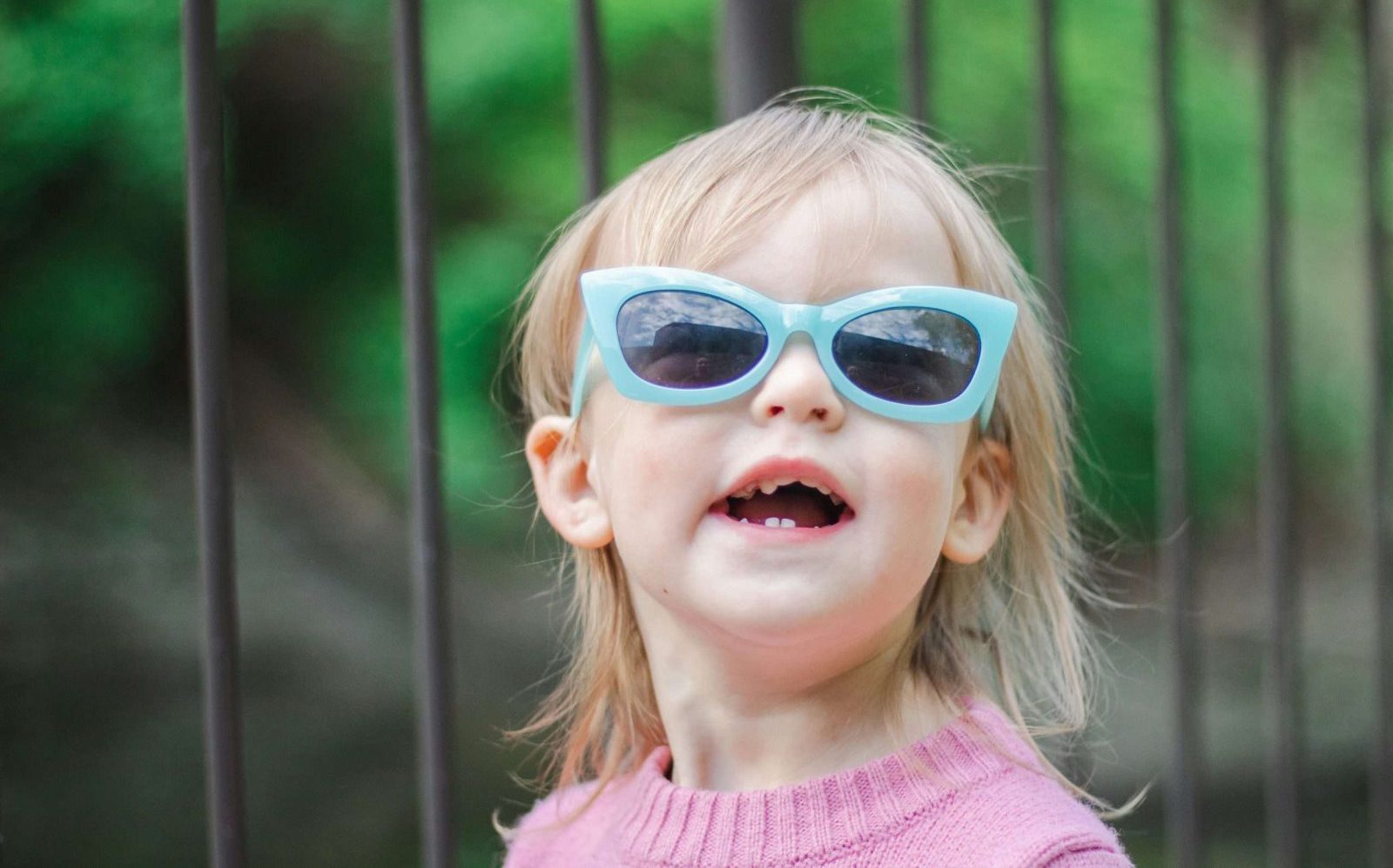 sean-foster-QC02B0ilp0M-unsplash A toddler with blonde hair smiling in her blue sunglasses